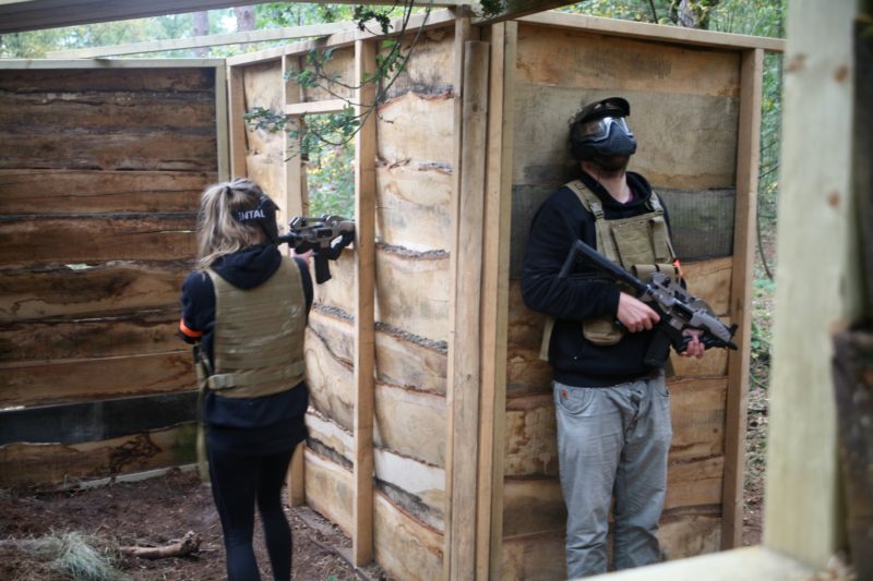 Twee collega's verdedigen samen een huisje op een airsoft bedrijfsfeest