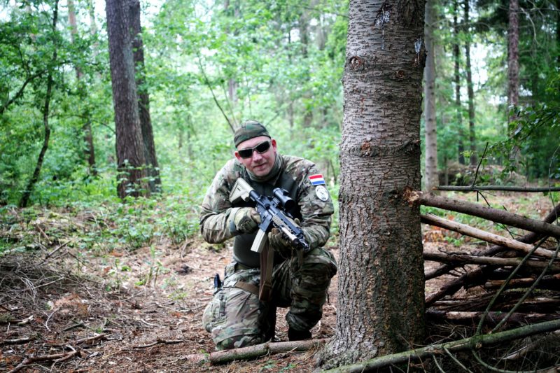 Airsofter mikt langs een boom
